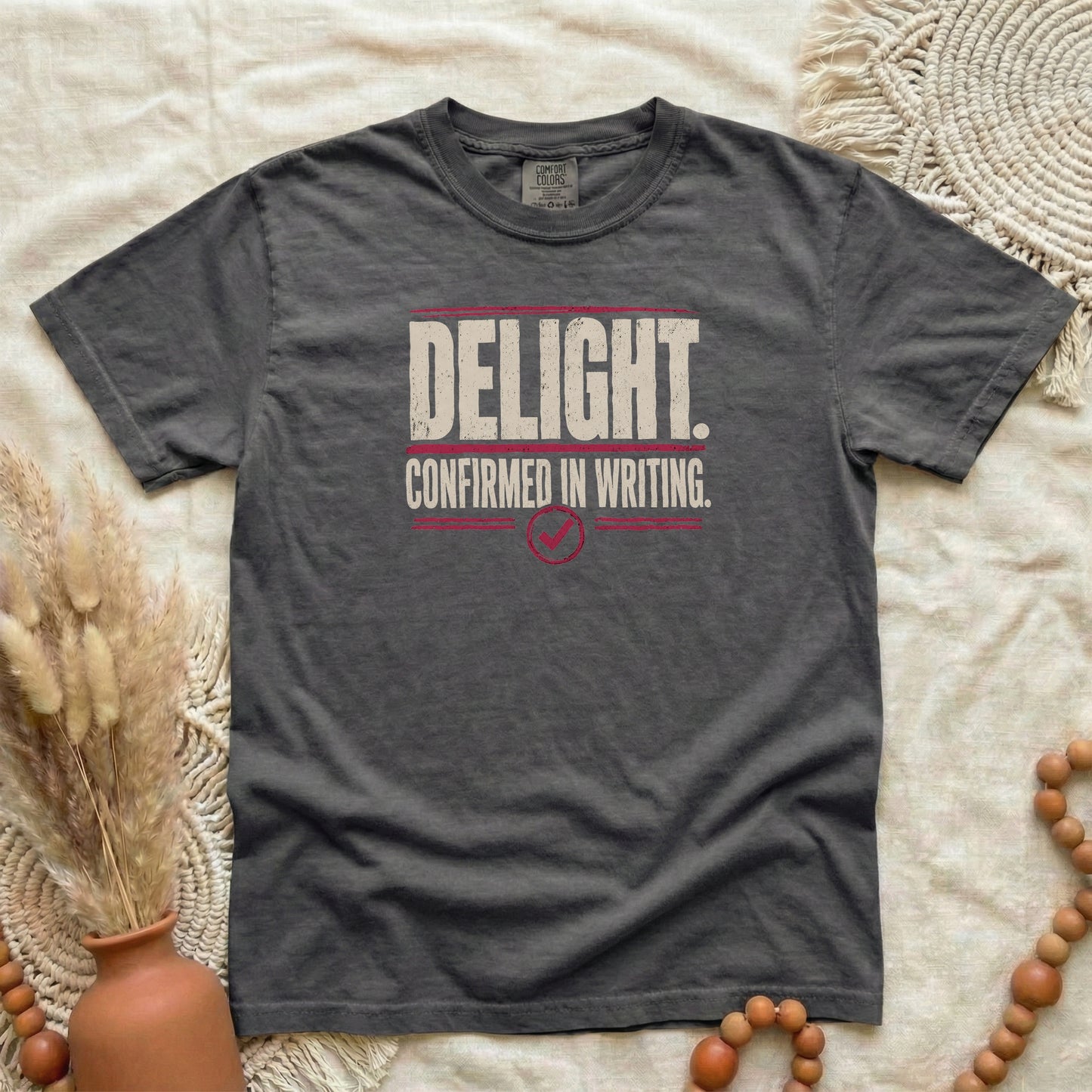 Pepper garment-dyed cotton tee printed with "Delight. Confirmed In Writing."