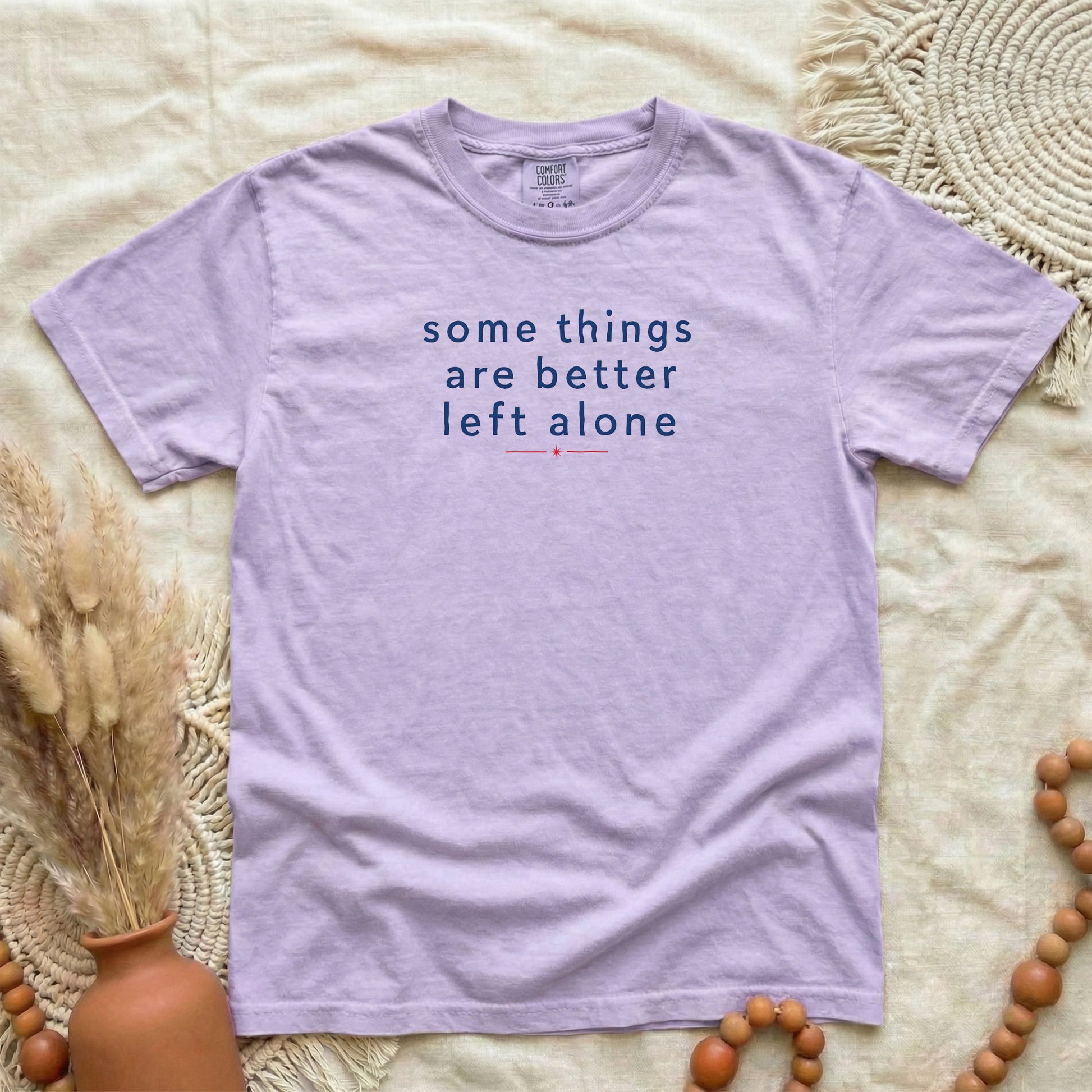 Orchid garment-dyed cotton tee printed with "Some Things Are Better Left Alone".