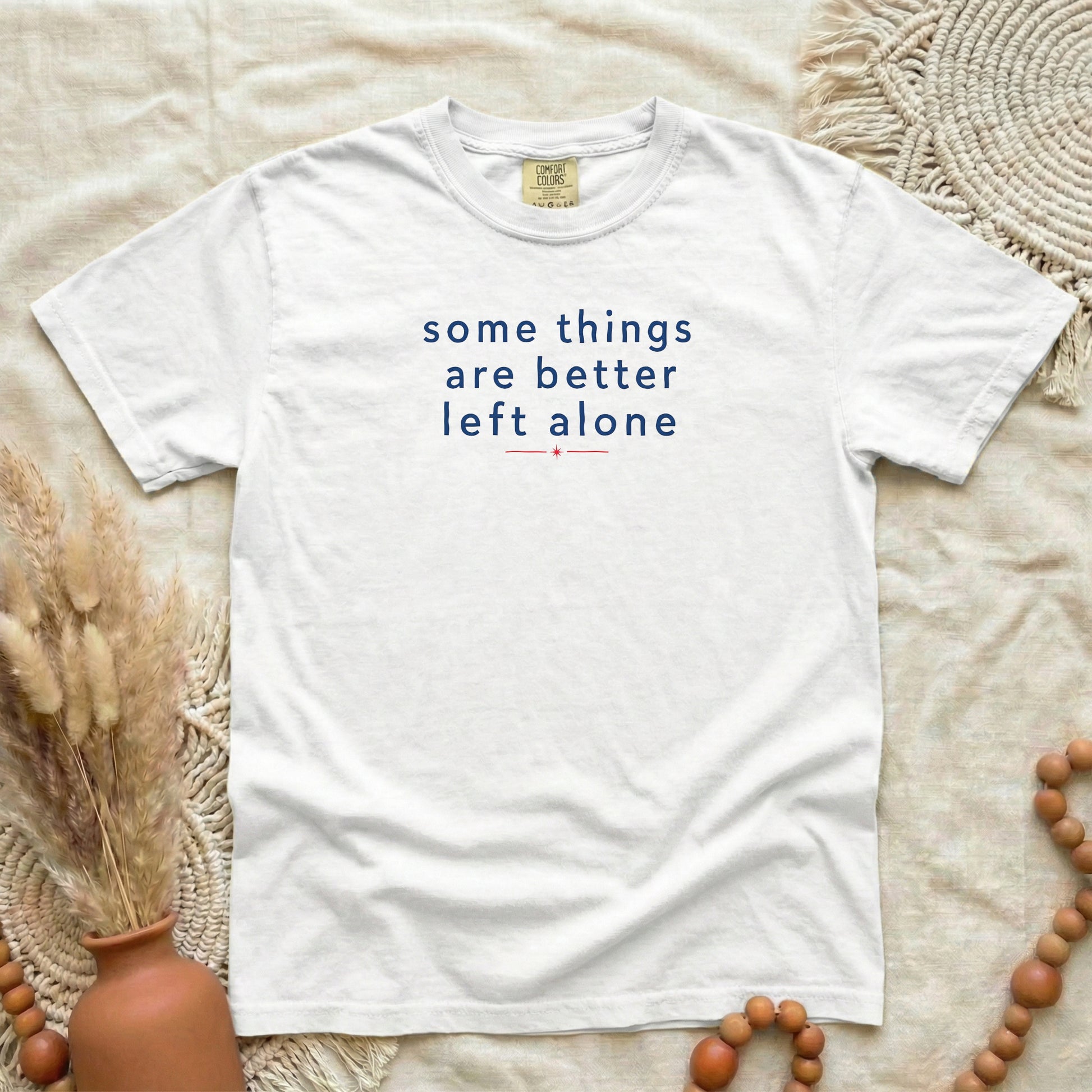 White garment-dyed cotton tee printed with "Some Things Are Better Left Alone".