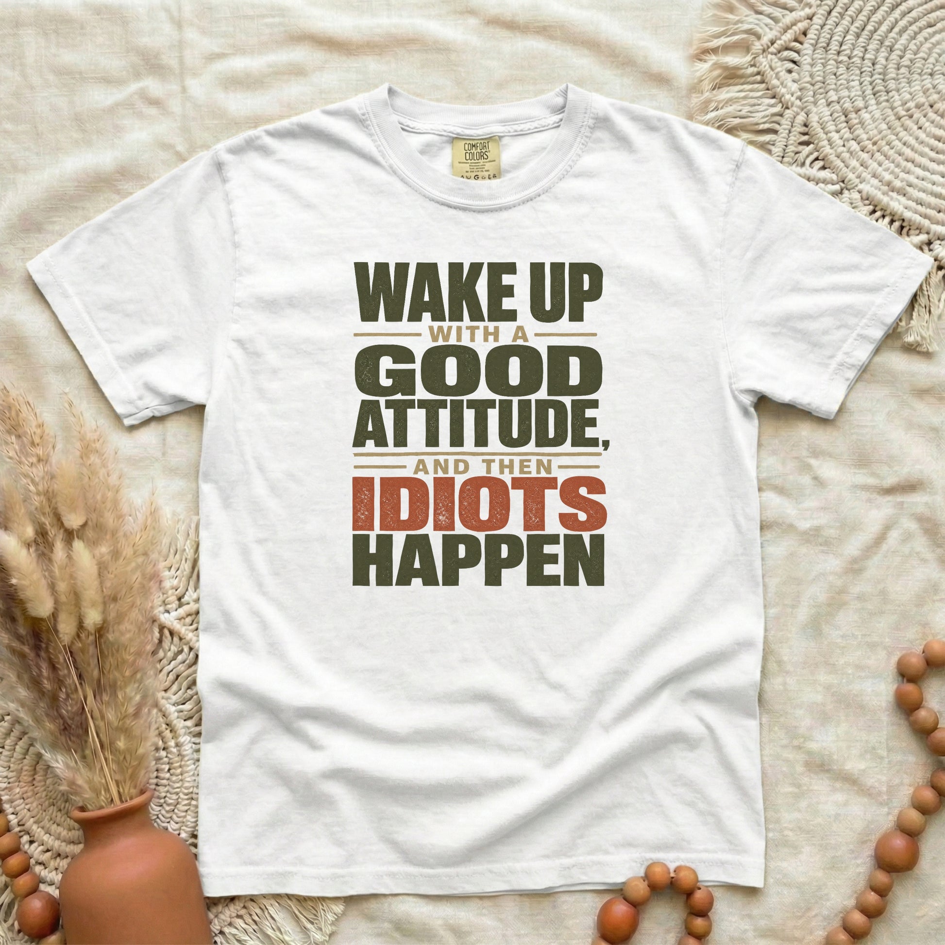 White garment-dyed cotton tee printed with "Wake Up With A Good Attitude, And Then Idiots Happen".