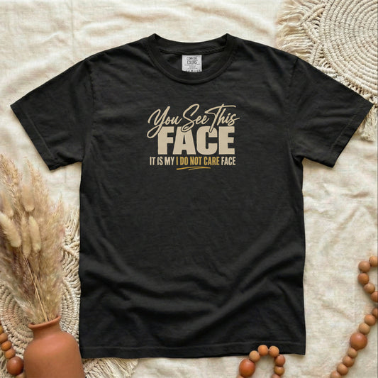 Black garment-dyed cotton tee printed with "You See This Face, It Is My I Do Not Care Face".