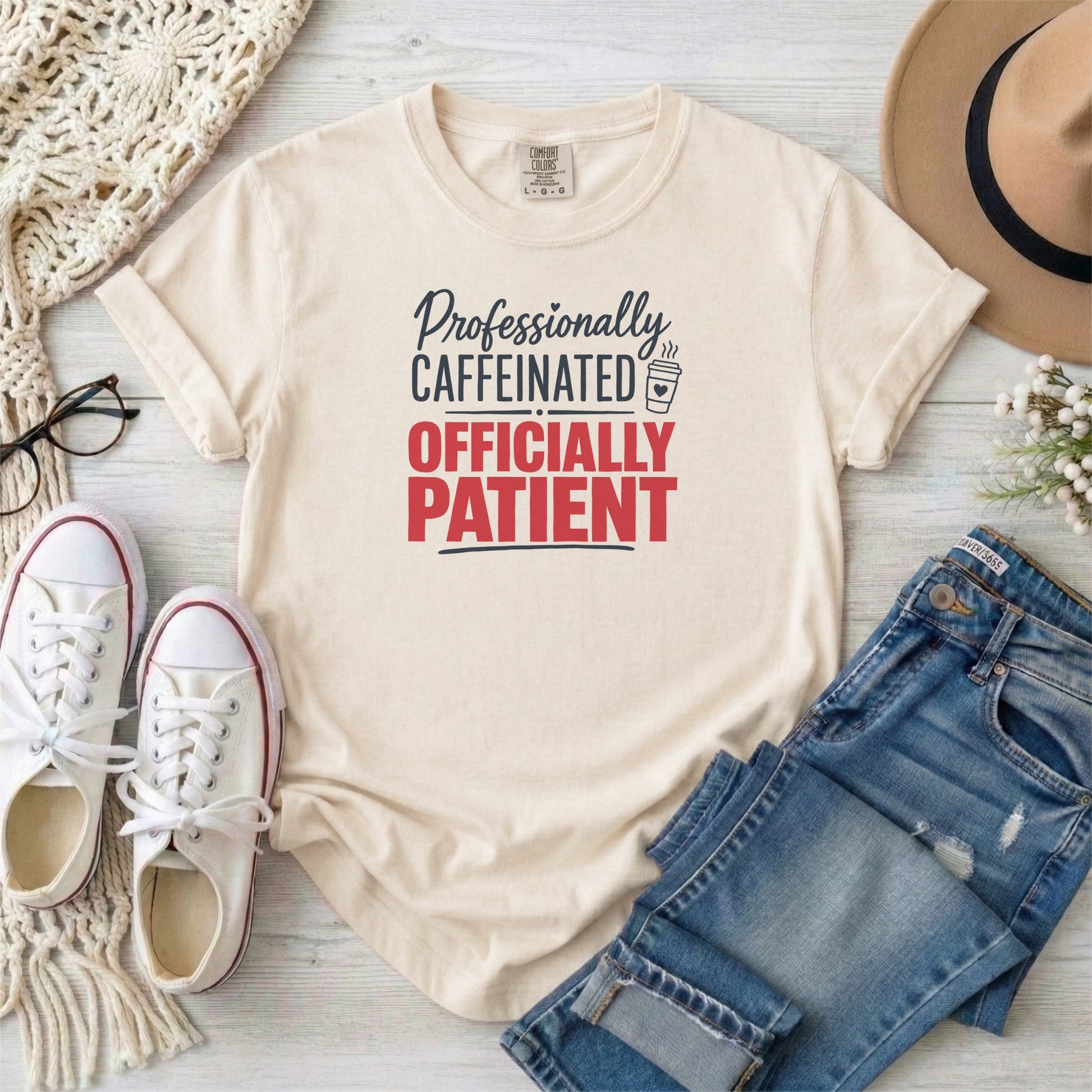 Ivory garment-dyed cotton tee printed with "Professionally Caffeinated, Officially Patient".